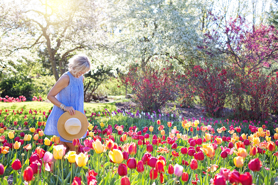 Woman enjoying garden of tulips on a sunny spring day